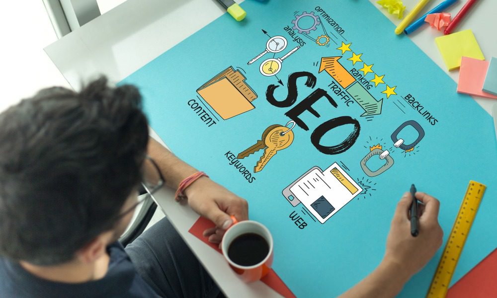 A designer drawing graphics for SEO keywords and content on blue paper. 